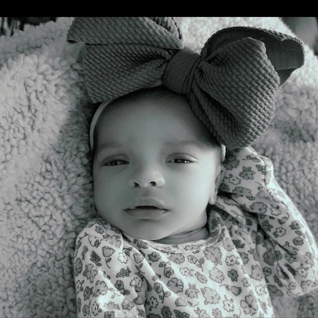 Amira is registered to the contest to win money with this photo: baby, baby_girl, black_and_white, blanket, bow, child, closeup, clothing, cozy, cute, face, floral_pattern, headband, infant, newborn, portrait, resting, sleepy, soft, texture