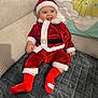 baby, child, santa_claus_outfit, red_clothing, smiling, couch, blanket, home_interior, holiday, festive, cute, infant, hat, plush, happy, sitting, indoor, person, face, sock