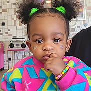 Lyrik is registered to the contest to win money with this photo: boombox, bracelet, bright_colors, child, colorful_sweater, curious, curly_hair, cute, earrings, face, fashion, green_scrunchies, hand_near_mouth, heart_stickers, indoor, person, portrait, retro_decor, toddler, young_child