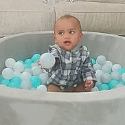 Kairo is registered to the contest to win money with this photo: toddler, child, ball_pit, plastic_balls, indoor, playtime, curious, checkered_shirt, seated, toy, colorful, young_child, smiling, fun, home, couch, soft_furniture, casual_clothing, baby, play