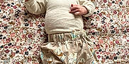 Marcel a rejoint le concours — aidez-le/la à gagner de superbes lots ! animal_print, baby, blanket, child, clothing, curious, cute, floral_pattern, head, indoors, infant, lying_down, pants, patterned_fabric, peaceful, portrait, skin, small_hands, socks, soft_light