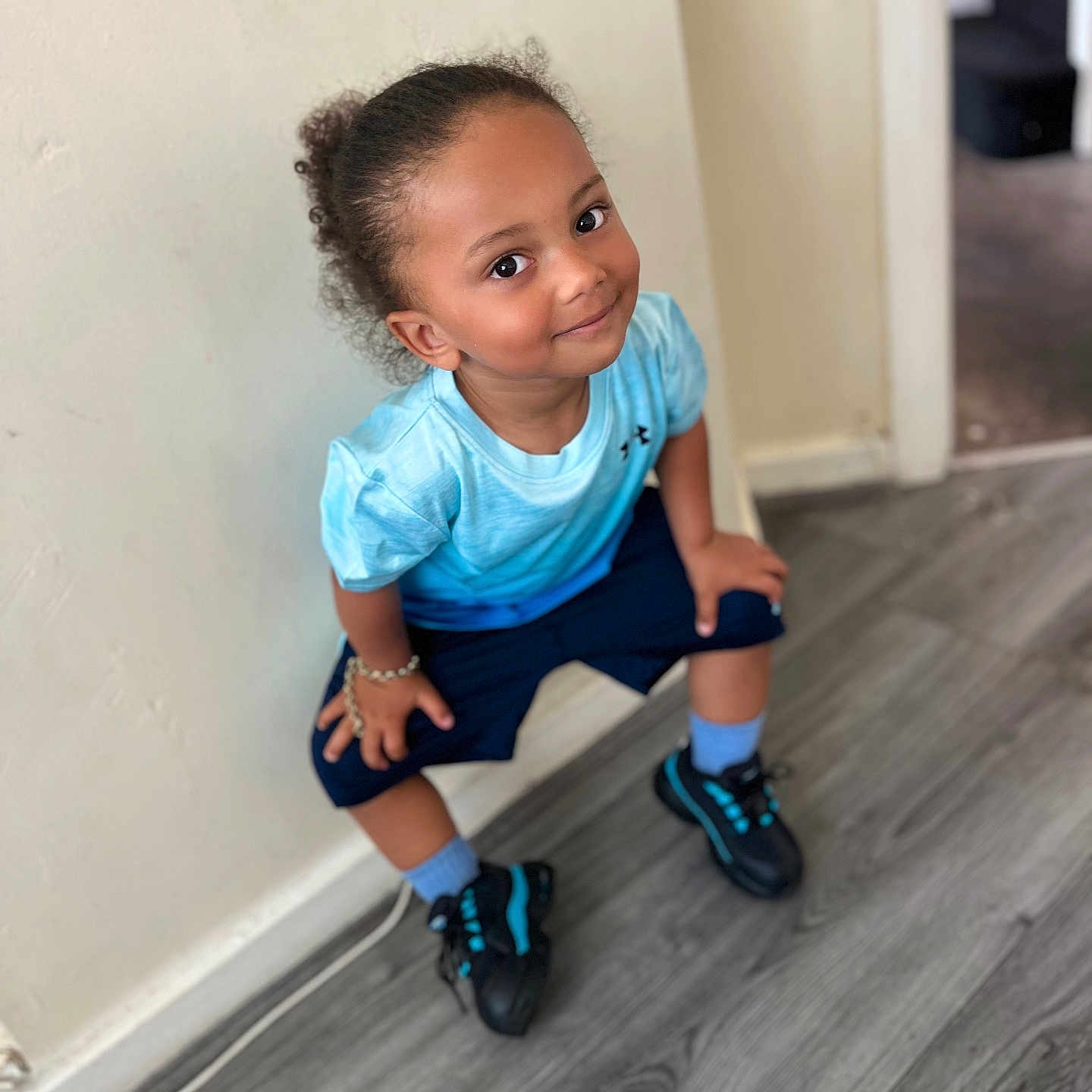 Kamilio joined the competition — help win amazing prizes! blue_shirt, bracelet, candid, casual_clothing, child, curly_hair, floor, happy, indoor, light, person, playing, portrait, shorts, smile, sneakers, sock, wall, wood_floor, young_child