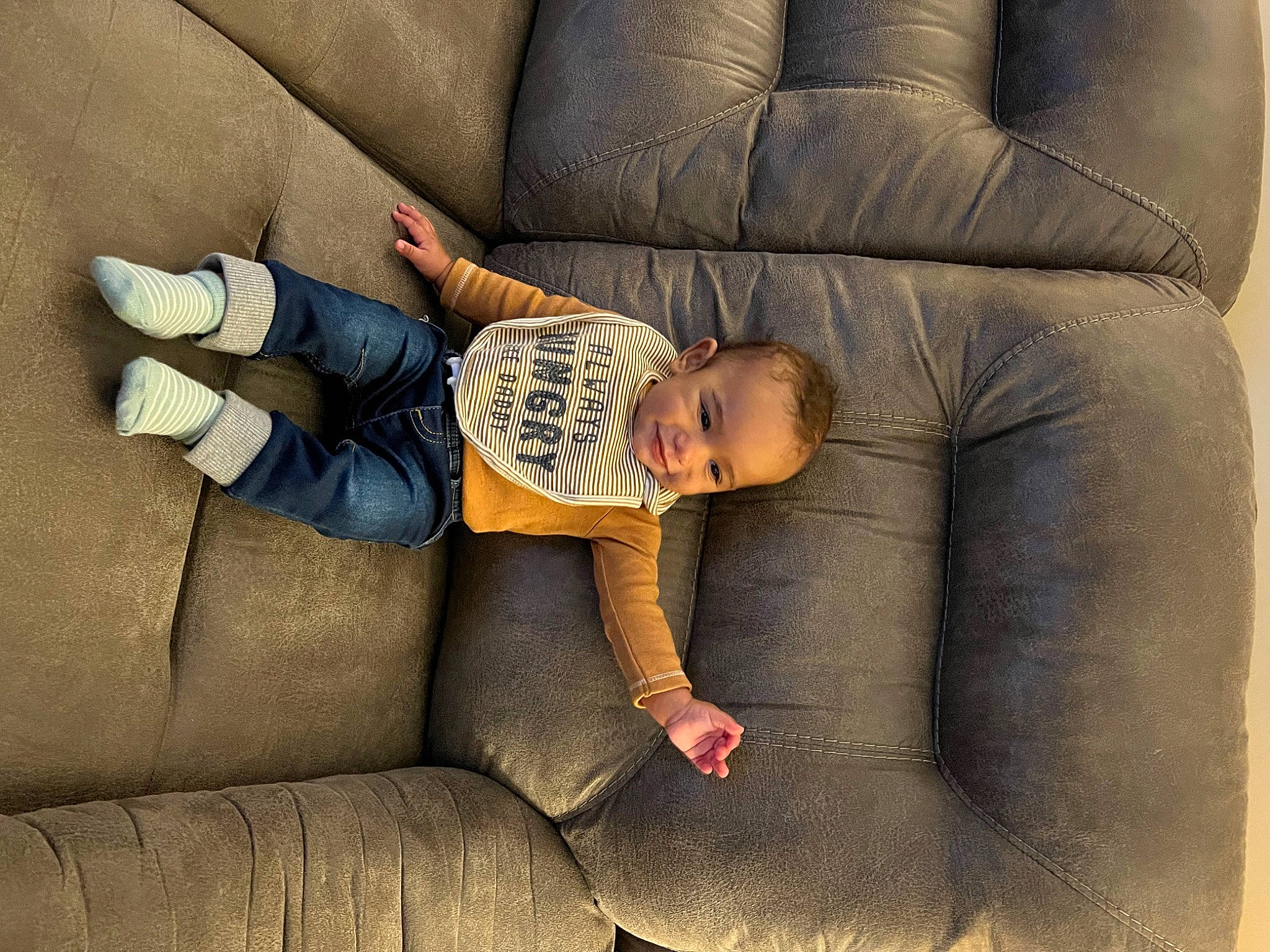 Bellamy is registered to the contest to win money with this photo: baby, baby_toddler_clothing, child, comfort, couch, flooring, furniture, human_leg, linens, living_room, pattern, person, rectangle, room, sitting, sock, sofa_bed, studio_couch, throw_pillow, toddler