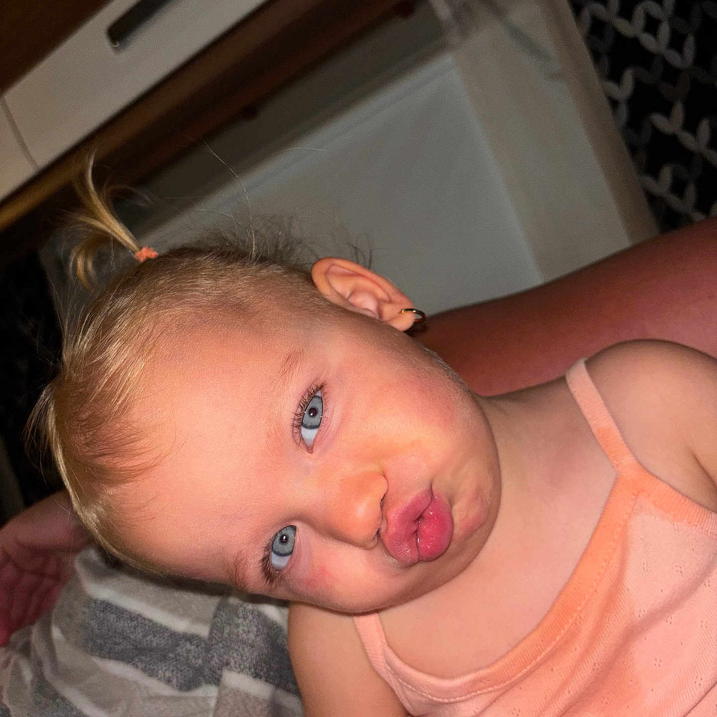 Laïzy participe au concours pour gagner de l'argent avec cette photo : blanket, blonde_hair, blue_eyes, child, closeup, cute, earring, expression, face, indoor, pattern, person, playful, pony_tail, portrait, skin, smile, tank_top, toddler, young_child