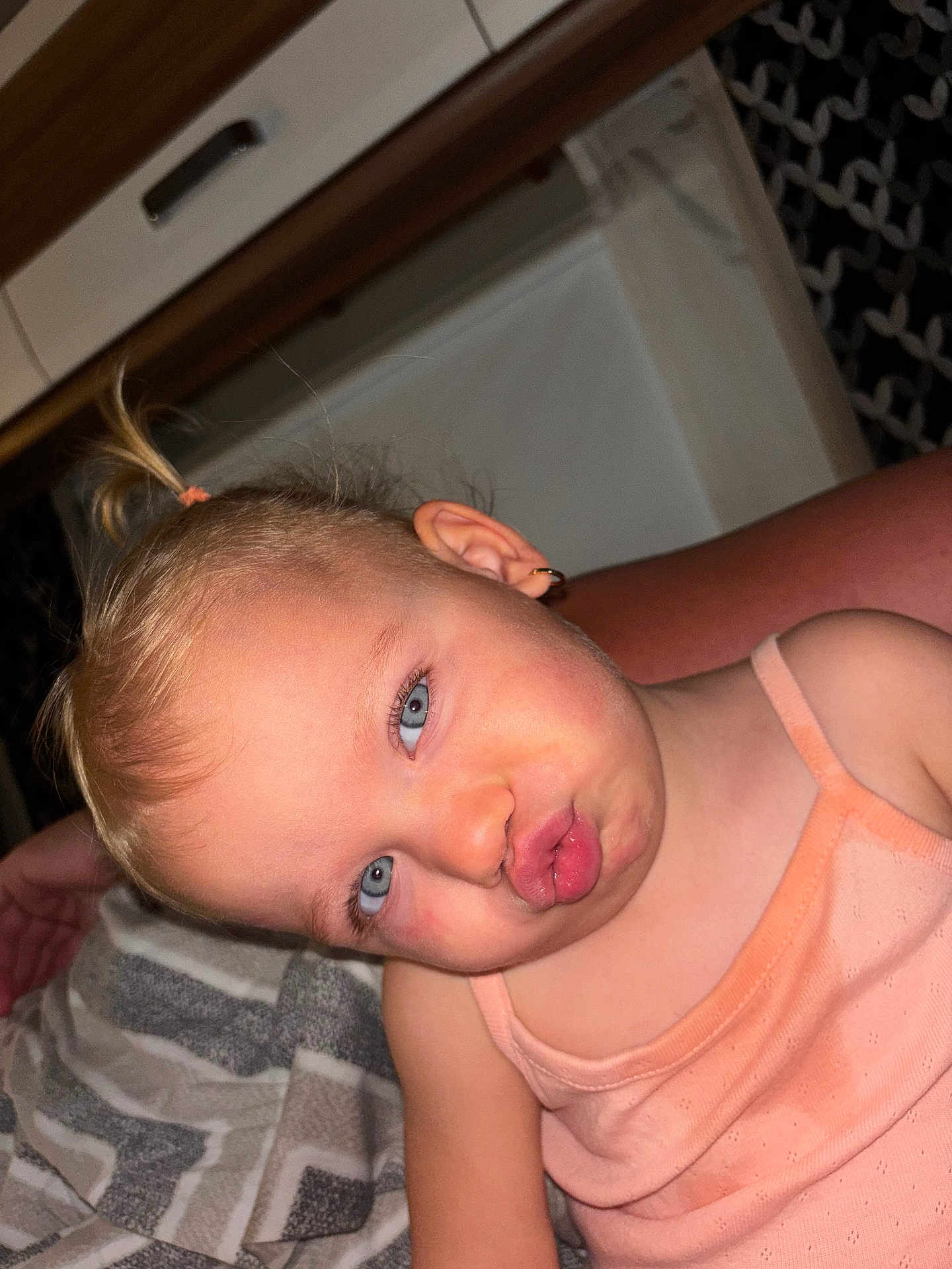 Laïzy participe au concours pour gagner de l'argent avec cette photo : blanket, blonde_hair, blue_eyes, child, closeup, cute, earring, expression, face, indoor, pattern, person, playful, pony_tail, portrait, skin, smile, tank_top, toddler, young_child
