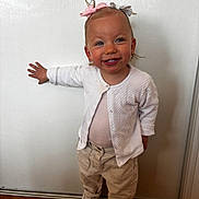 Laïzy a rejoint le concours — aidez-le/la à gagner de superbes lots ! beige_pants, casual_clothing, child, cute, earrings, full_body, hair_bows, happy, indoor, light_background, person, playful, portrait, smiling, sneakers, standing, toddler, white_cardigan, wooden_floor, young_child