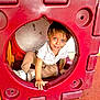 beige_pants, boy, candid, casual_clothing, child, curious, cute, daylight, fun, happy, outdoor, play, play_structure, playground, portrait, red, smiling, sneakers, white_shirt, young