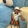 Darrian is registered to the contest to win money with this photo: baby, child, teddy_bear, plush_toy, blue, onesie, cap, sneakers, gold_chain, bow_tie, smiling, happy, cute, indoor, soft_texture, couch, blanket, fashion, accessories, portrait
