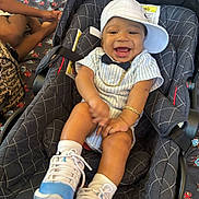 Darrian joined the competition — help win amazing prizes! baby, child, smiling, car_seat, cap, sneakers, gold_chain, bow_tie, striped_clothing, happy, indoor, person, footwear, seat, patterned_blanket, cushion, baby_shoes, infant, cute, joy