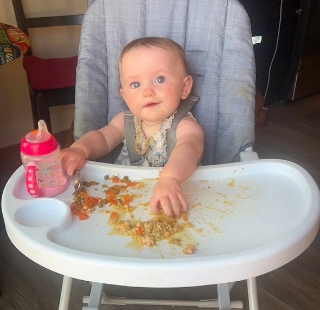 Sunny is registered to the contest to win money with this photo: baby, high_chair, food, messy, sippy_cup, indoor, child, cute, blue_eyes, feeding, toddler, plate, floor, chair, table, person, meal, kitchen, hand, clothing