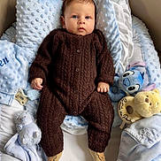 Owen participe au concours pour gagner de l'argent avec cette photo : baby, infant, child, portrait, blanket, pillow, plush_toy, stuffed_animal, blue, brown_clothing, knitwear, socks, bed, nursery, soft_texture, gaze, hands, feet, cozy, smile