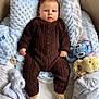 baby, infant, child, portrait, blanket, pillow, plush_toy, stuffed_animal, blue, brown_clothing, knitwear, socks, bed, nursery, soft_texture, gaze, hands, feet, cozy, smile