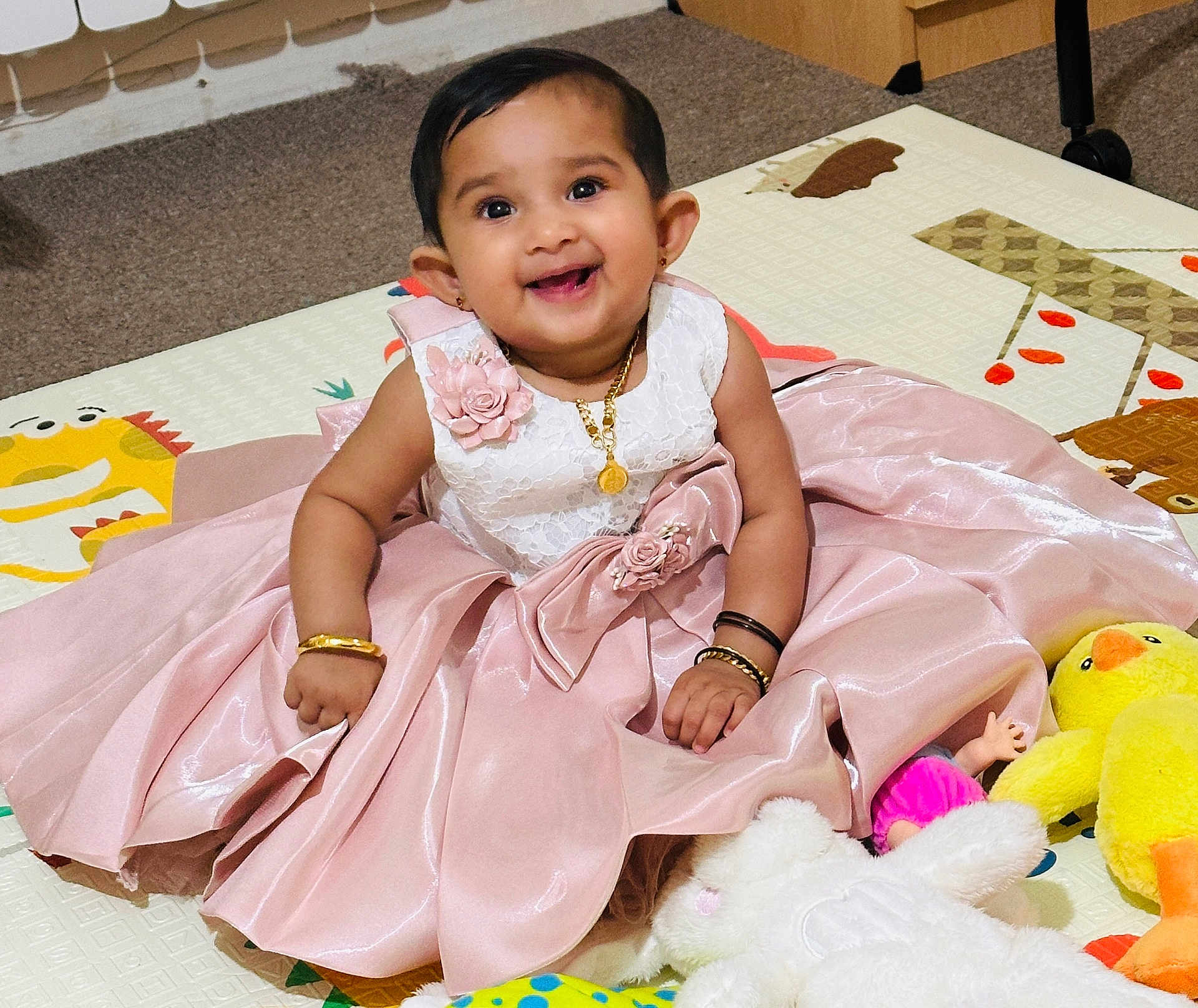 Deona joined the competition — help win amazing prizes! baby, child, dress, pink_dress, smile, happy, play_mat, plush_toy, stuffed_animal, yellow_duck, sitting, bracelet, necklace, indoor, carpet, floor, cute, portrait, young_child, person