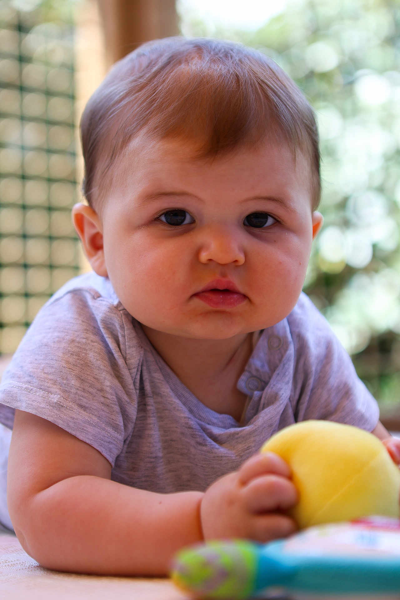 Marin participe au concours pour gagner de l'argent avec cette photo : baby, child, infant, face, eyes, cheeks, arm, hand, toy, yellow_ball, clothing, shirt, skin, portrait, closeup, indoor, soft_light, curious, lying_down, cute