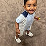 baby, carpet, casual_clothing, child, cute, expression, food, footwear, hair, happy, holding, indoor, person, playful, romper, shorts, smiling, standing, toddler, young
