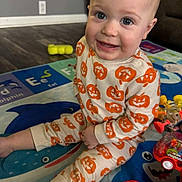Ayden is registered to the contest to win money with this photo: baby, child, pajamas, pumpkin_pattern, smile, play_mat, toy, floor, indoor, happy, person, cute, sitting, infant, face, head, legs, hand, colorful, home