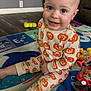 baby, child, pajamas, pumpkin_pattern, smile, play_mat, toy, floor, indoor, happy, person, cute, sitting, infant, face, head, legs, hand, colorful, home