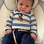 baby, infant, mickey_mouse, striped_shirt, navy_pants, baby_seat, pacifier, cushion, clothing, cute, child, indoors, portrait, smiling, relaxed, hands, feet, comfort, young, person