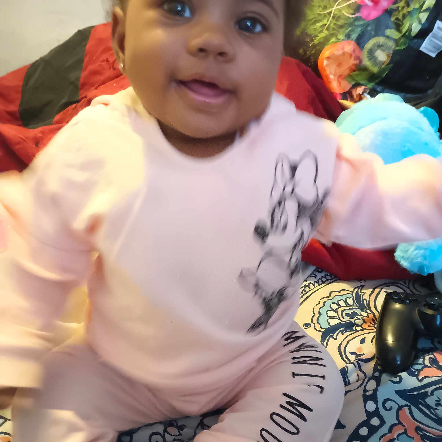 Aniyah'Mariee joined the competition — help win amazing prizes! baby, bedspread, blue_toy, child, cute, face, game_controller, hand, happy, home, indoor, minnie_mouse, motion_blur, pajamas, patterned_textile, person, pink_clothing, plush_toy, smiling, young_child