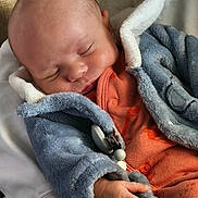 Pablo participe au concours pour gagner de l'argent avec cette photo : baby, sleeping, infant, blue_jacket, orange_onesie, hand, face, cozy, soft_texture, child, newborn, peaceful, resting, warm_clothing, cute, person, indoor, close_up, skin, fleece