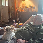 Dusty Bottoms joined the competition — help win amazing prizes! dog, person, indoor, lamp, recliner, furniture, sleeping, pet, small_dog, relaxing, beard, gray_hair, table, bottle, container, window, door, casual_clothing, cozy, home