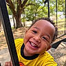 Dexter is registered to the contest to win money with this photo: child, closeup, curly_hair, daylight, face, grinning, happy, head, joyful, nature, outdoor, park, play_equipment, playground, portrait, smiling, teeth, toddler, trees, yellow_shirt