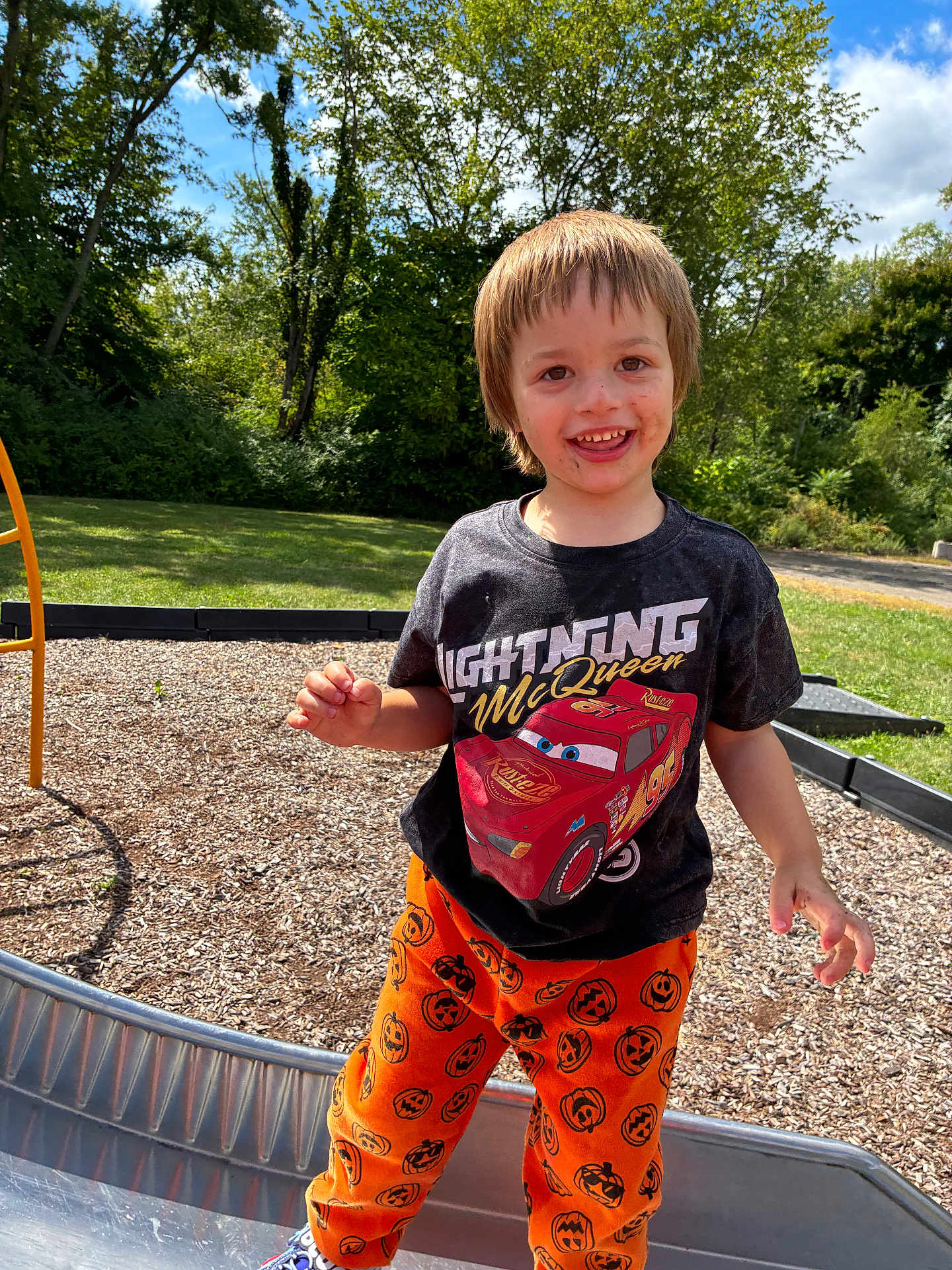 Uhtred joined the competition — help win amazing prizes! child, boy, smiling, playground, slide, outdoor, daytime, tshirt, pants, orange, black, pumpkin, face, dirt, grass, trees, sky, sunny, fun, happy