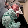 newborn, baby, sleeping, infant, tattoo, adult, hospital, medical_equipment, nasal_tube, onesie, clothing, person, hand, arm, furniture, chair, hospital_room, resting, cute, comfort
