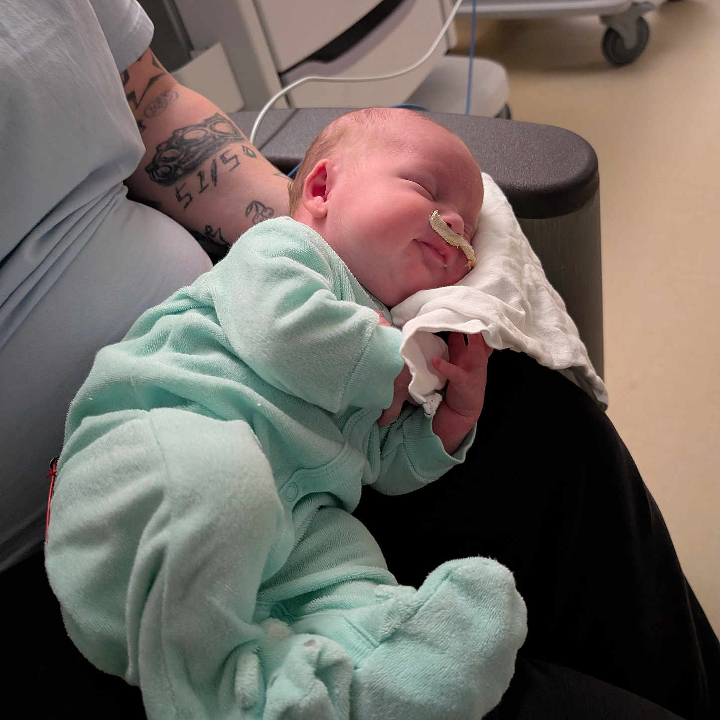 Eli joined the competition — help win amazing prizes! newborn, baby, sleeping, infant, tattoo, adult, hospital, medical_equipment, nasal_tube, onesie, clothing, person, hand, arm, furniture, chair, hospital_room, resting, cute, comfort