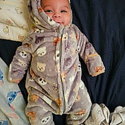 Armani is registered to the contest to win money with this photo: baby, infant, child, onesie, hoodie, pajamas, blanket, bed, smile, face, eyes, cute, cozy, zipper, pattern, plush_pattern, fabric, lying_down, sleeve, footie
