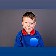 Otis is registered to the contest to win money with this photo: child, boy, smiling, portrait, blue_sweater, red_collar, happy, face, casual_clothing, studio, background, cute, young, short_hair, indoors, person, headshot, expression, positive, friendly