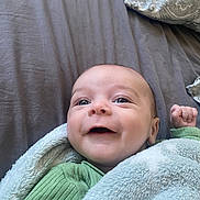 Malo a rejoint le concours — aidez-le/la à gagner de superbes lots ! baby, infant, smile, blanket, green_clothing, bed, pillow, face, happy, cute, child, person, skin, lying_down, cozy, soft_texture, indoor, portrait, newborn, expression