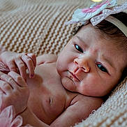Mariana is registered to the contest to win money with this photo: baby, child, close_up, cute, expression, face, flower, hand, headband, indoors, infant, knitted_blanket, lying_down, newborn, pink, portrait, skin, skirt, soft_texture, tulle