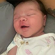 Mariana is registered to the contest to win money with this photo: baby, sleeping, smiling, onesie, infant, tattoo, closeup, person, cute, newborn, love, comfort, skin, face, head, child, portrait, clothing, resting, family
