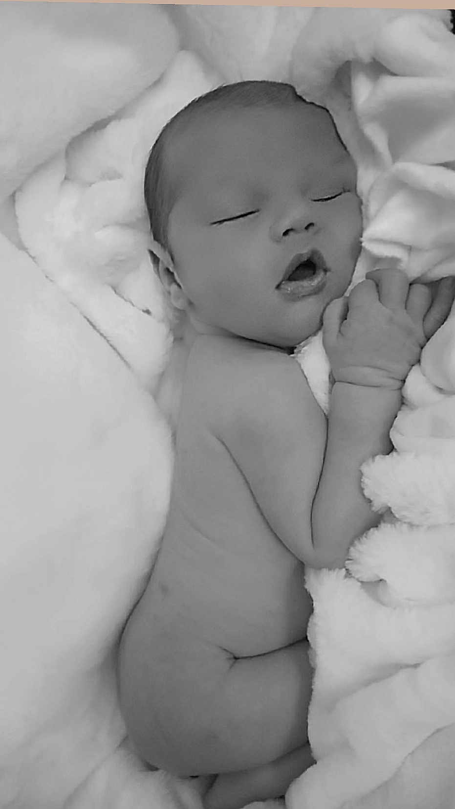 Travise is registered to the contest to win money with this photo: baby, newborn, sleeping, blanket, soft, cute, infant, peaceful, resting, skin, hand, face, portrait, child, adorable, monochrome, black_and_white, cozy, toddler, lying_down