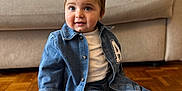 Arié participe au concours pour gagner de l'argent avec cette photo : baby, blanket, casual, child, couch, cozy, cute, denim_jacket, denim_pants, fashion, flooring, home, indoor, portrait, sitting, smile, toddler, white_shirt, white_socks, wooden_floor