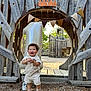 child, toddler, birthday, balloon, number_one, wooden_playground, outdoor, smile, hat, overalls, shoes, playground_equipment, celebration, happy, daylight, wood, natural_light, person, nature, fun