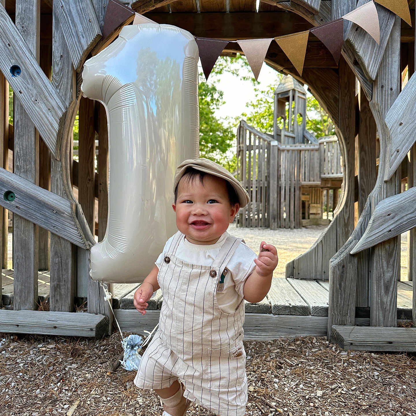 Parvin is registered to the contest to win money with this photo: baby, balloon, birthday, cap, celebration, child, daylight, footwear, fun, happy, nature, number_one, outdoor, overalls, person, playground, sand, smile, toddler, wood