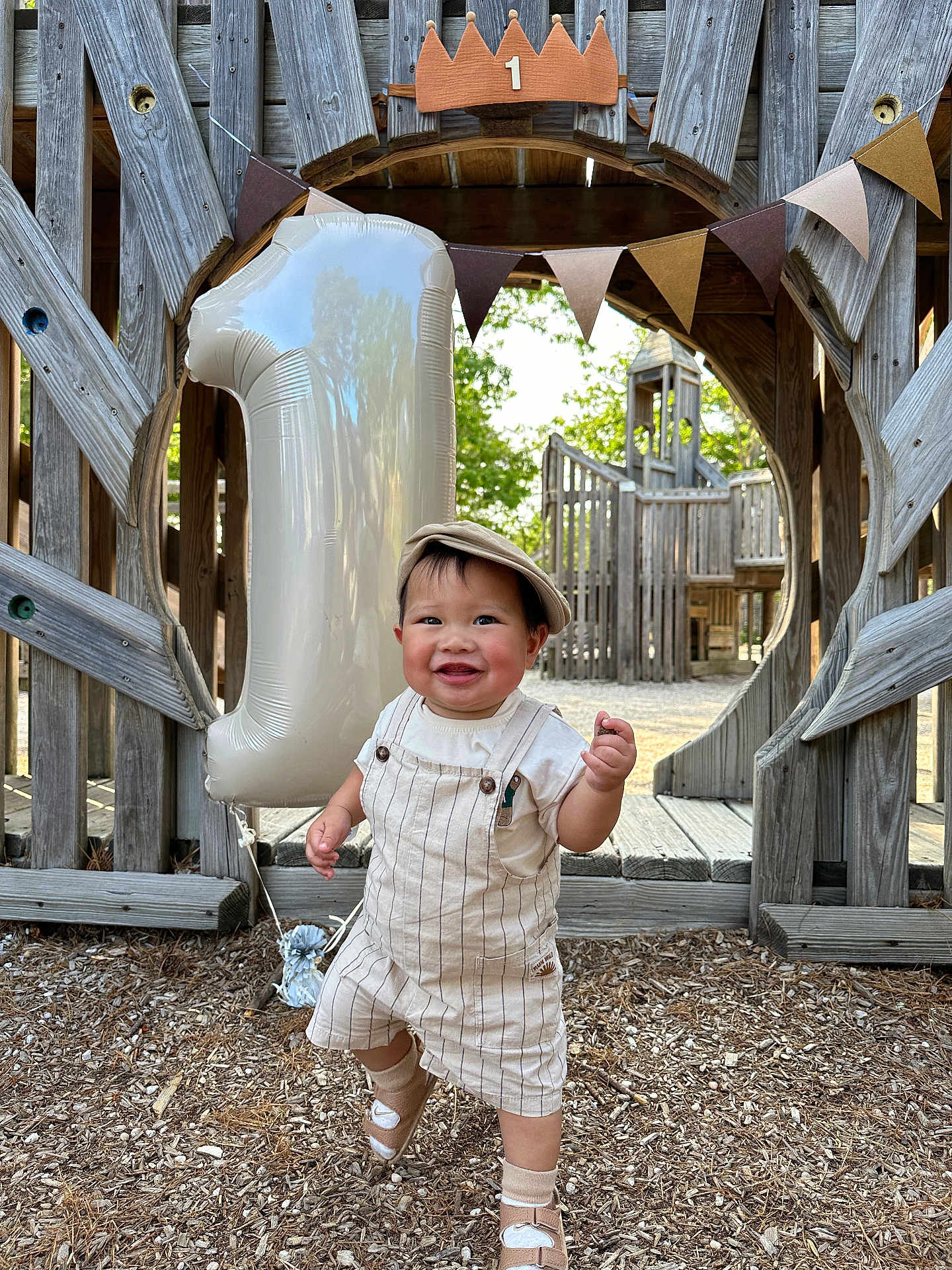 Parvin is registered to the contest to win money with this photo: toddler, child, birthday, balloon, number_one, cap, overalls, outdoor, playground, wood, smile, happy, celebration, baby, footwear, nature, daylight, person, sand, fun