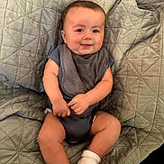Elijah joined the competition — help win amazing prizes! baby, smiling, infant, onesie, socks, blanket, quilted, drool, cute, child, portrait, sitting, happy, chubby_cheeks, indoors, young_child, face, person, cozy, casual