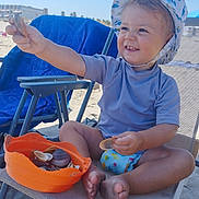 Mathys participe au concours pour gagner de l'argent avec cette photo : barefoot, beach, blue_sky, bucket, chair, child, diaper, happy, hat, outdoor, play, sand, seashell, smile, summer, sunhat, sunlight, toddler, toy, vacation