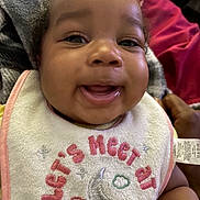 Kahlani is registered to the contest to win money with this photo: baby, smiling, bib, drool, close_up, face, child, infant, blanket, embroidery, crescent_moon, stars, happy, indoors, person, cute, warm, cozy, pink, red