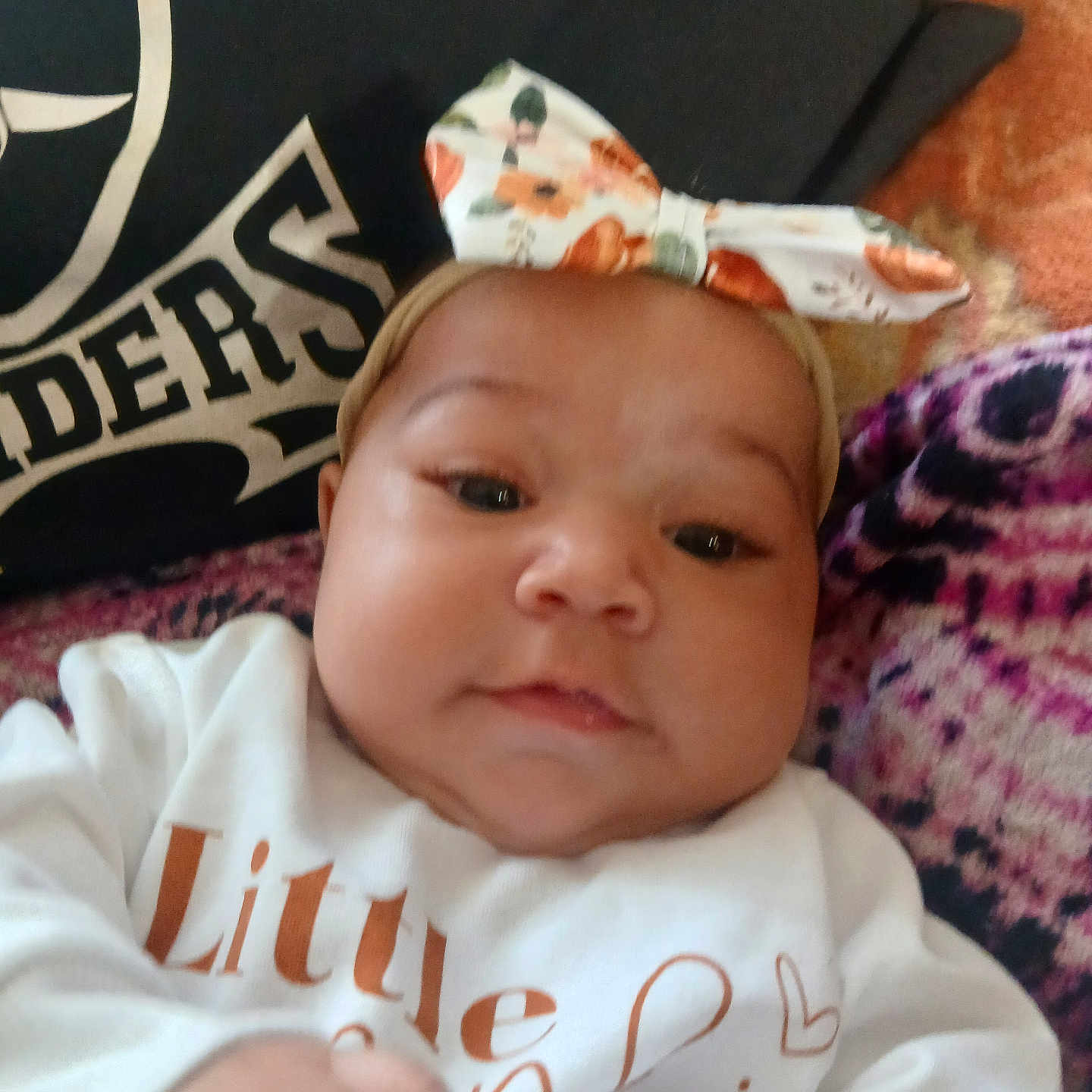 Emiliana joined the competition — help win amazing prizes! baby, blanket, bow, child, closeup, clothing, cute, face, hand, headband, indoors, infant, pattern, person, pillow, portrait, skin, text, white_shirt, young