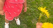 Valerie Alonzo is registered to the contest to win money with this photo: child, toddler, grass, flower, dandelion, hand, outdoor, greenery, curious, summer, casual_clothing, sandals, person, nature, young_child, portrait, daylight, playing, cute, expression