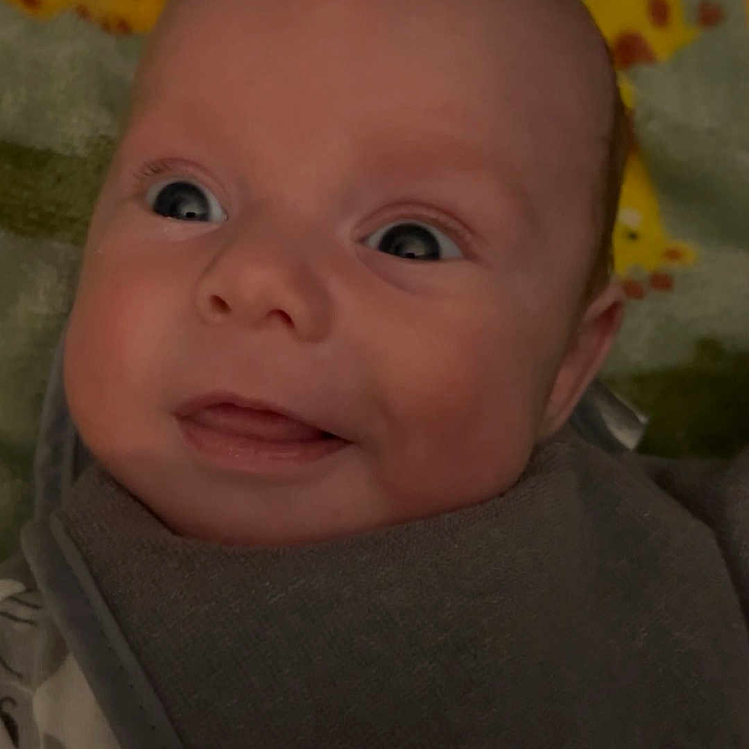 Dean is registered to the contest to win money with this photo: baby, blanket, bodypart, bonnet, clothing, cushion, face, finger, hand, happy, hat, head, homedecor, knitwear, mouth, newborn, person, photography, portrait, quilt