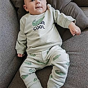 Luca participe au concours pour gagner de l'argent avec cette photo : baby, child, clothing, comfortable, couch, cozy, crocodile_pattern, cute, face, indoors, infant, looking_up, pajamas, pillow, relaxed, seated, small_hands, smile, socks, soft_lighting