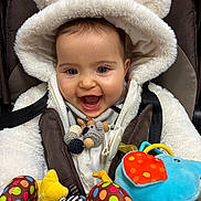 Lya a rejoint le concours — aidez-le/la à gagner de superbes lots ! baby, child, smiling, fluffy, hood, bear_ears, stroller, toy, plush, colorful, blue_elephant, polka_dot, yellow_star, happy, cute, close_up, infant, seat_belt, warm_clothing, playful