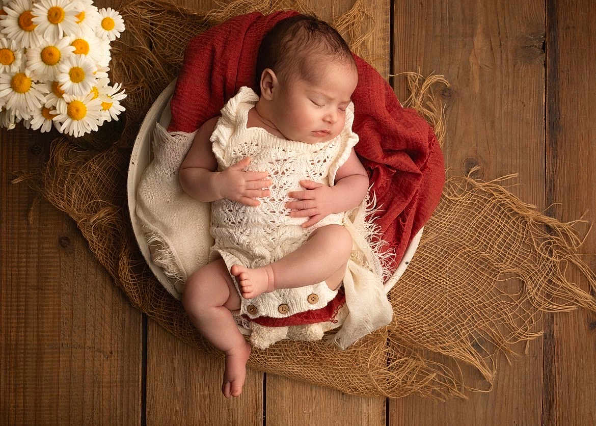 Lya a rejoint le concours — aidez-le/la à gagner de superbes lots ! baby, newborn, sleeping, knitwear, blanket, bowl, wooden_floor, flowers, daisies, cozy, infant, peaceful, soft_lighting, portrait, cute, resting, hands, feet, fabric, natural