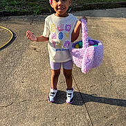 Kyrah is registered to the contest to win money with this photo: child, smiling, outdoor, easter_eggs, basket, concrete, sunlight, tshirt, shorts, shoes, happy, grass, beads, braids, playful, daylight, young, person, holiday, spring