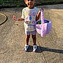child, smiling, outdoor, easter_eggs, basket, concrete, sunlight, tshirt, shorts, shoes, happy, grass, beads, braids, playful, daylight, young, person, holiday, spring